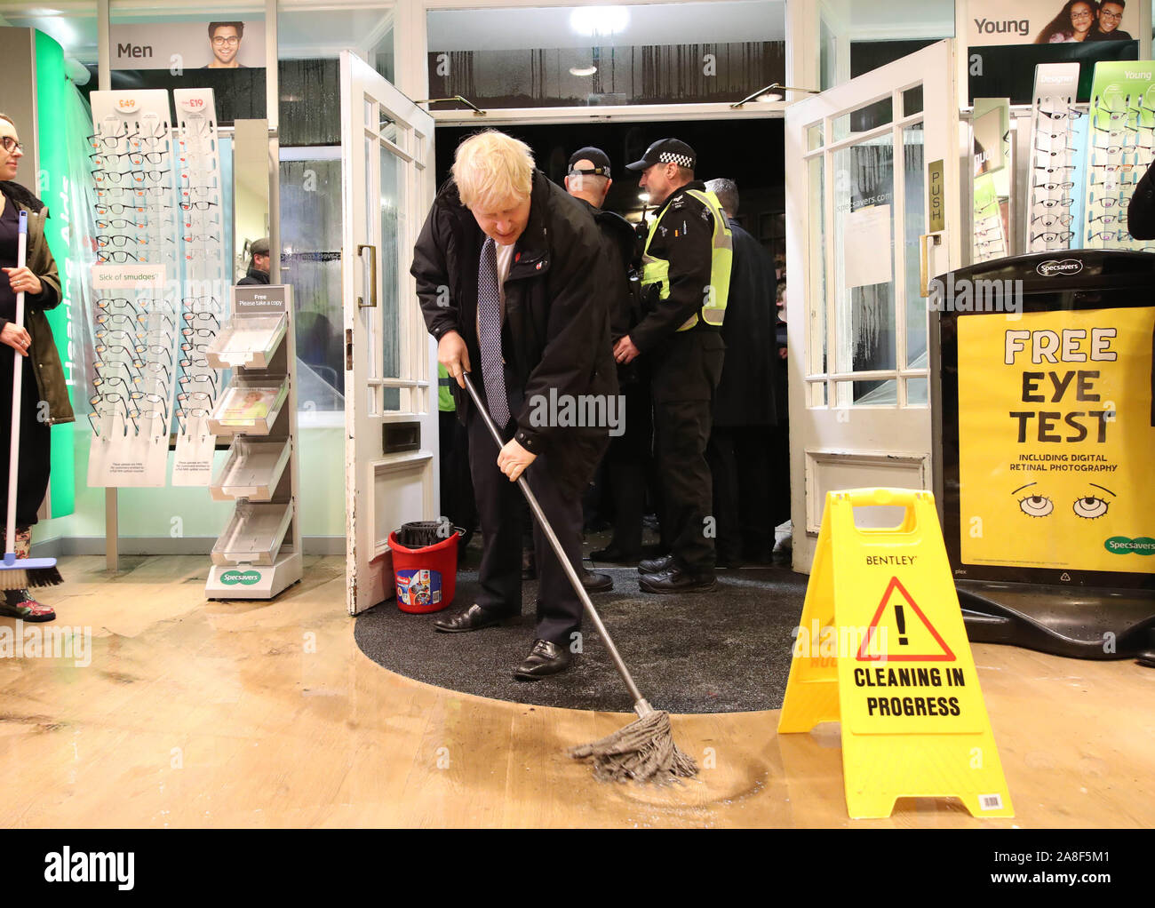 Premier ministre Boris Johnson aide à nettoyer à un opticien comme il rend visite à Matlock, Derbyshire pour voir l'inondation. Banque D'Images