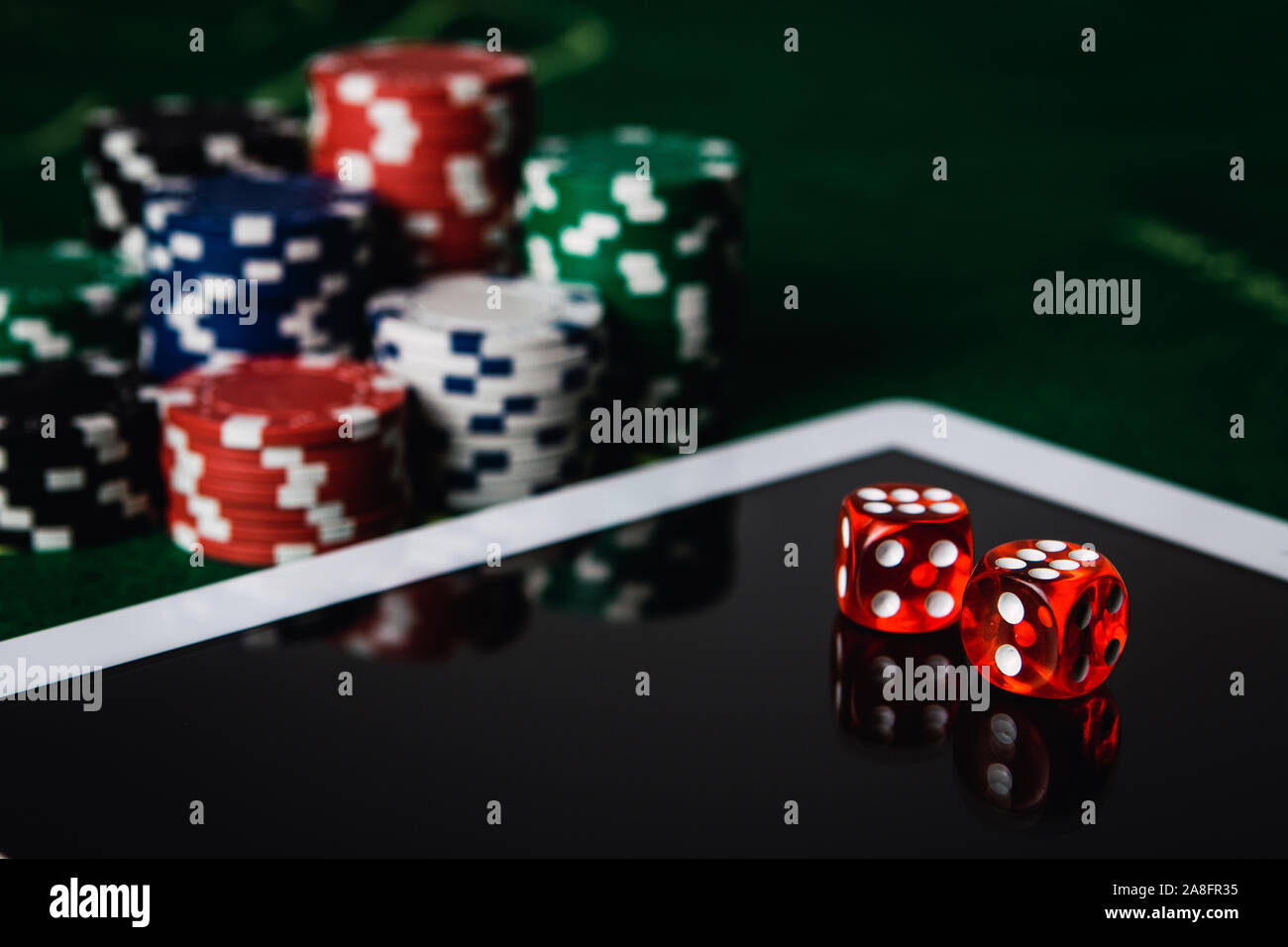 Les jeux en ligne et de jeu concept. Feutre vert, tablette numérique, red dés et des jetons de poker Banque D'Images