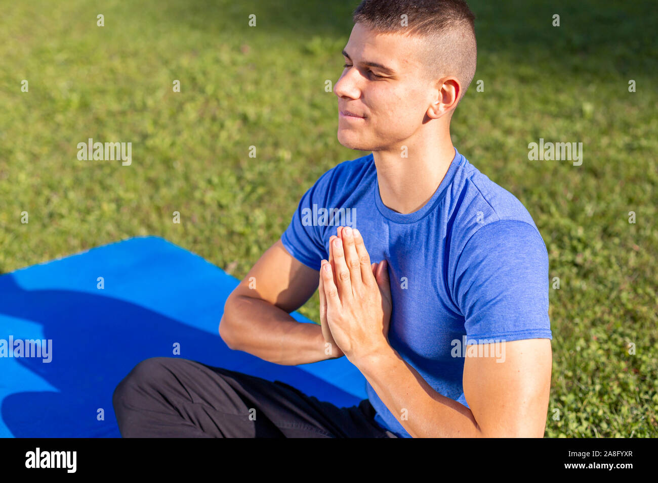 Jeune homme portant des vêtements de sport assis dans le parc l'exercice de yoga Banque D'Images