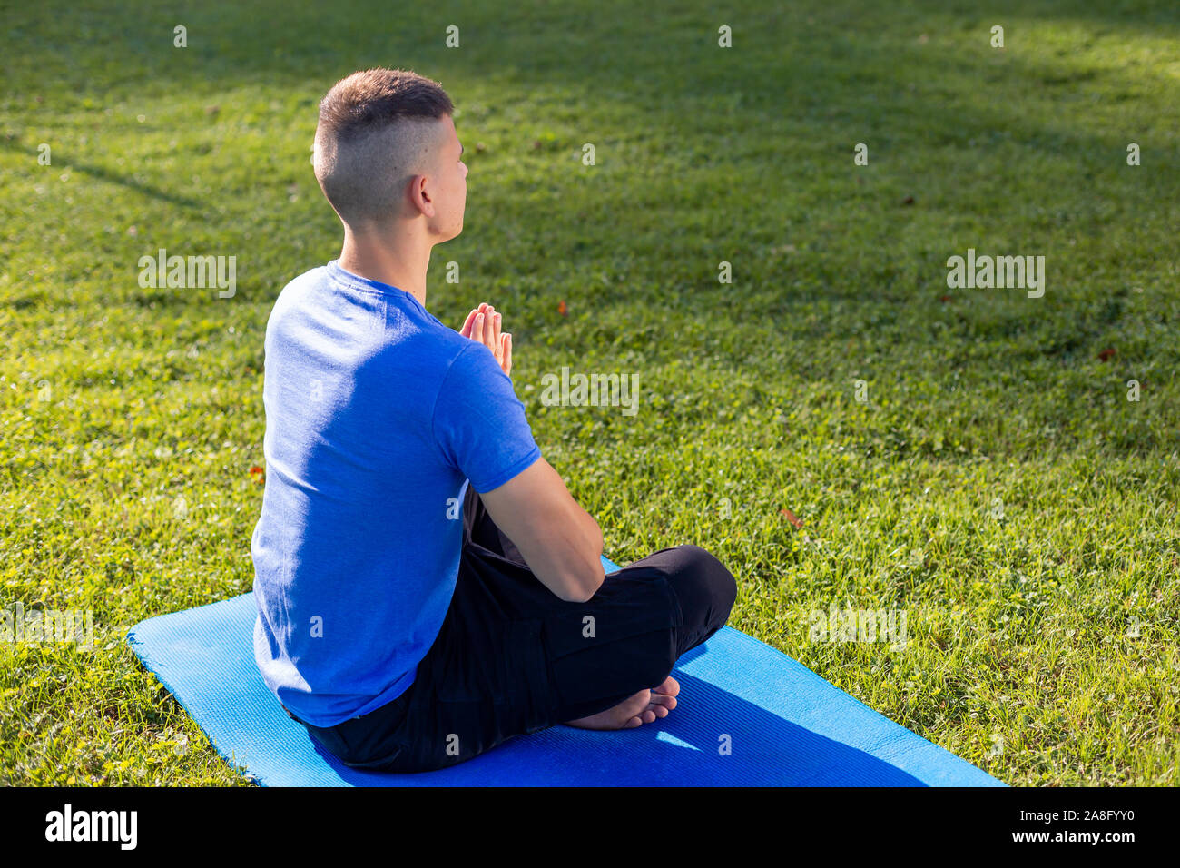 Jeune homme portant des vêtements de sport assis dans le parc l'exercice de yoga Banque D'Images