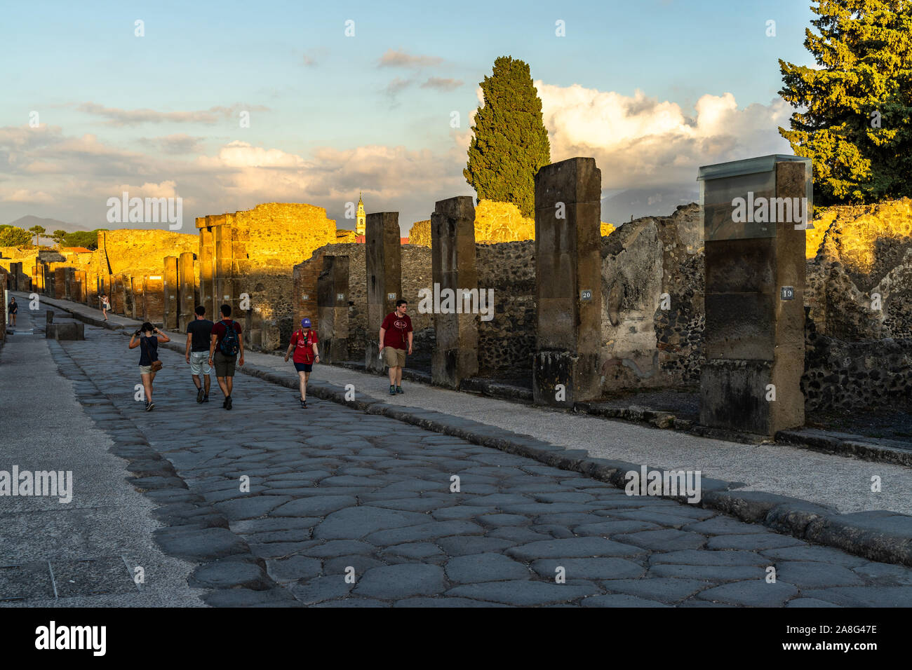 Les visiteurs parmi les ruines de Pompéi marcher sur la Via dell'abbondanza au coucher du soleil. Pompéi, Italie, Octobre 2019 Banque D'Images