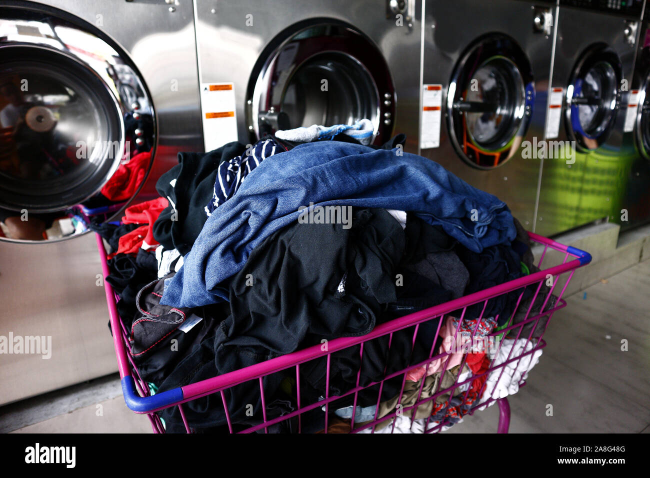 Photo d'un tas de linge propre dans un panier en face de machines à laver  Photo Stock - Alamy