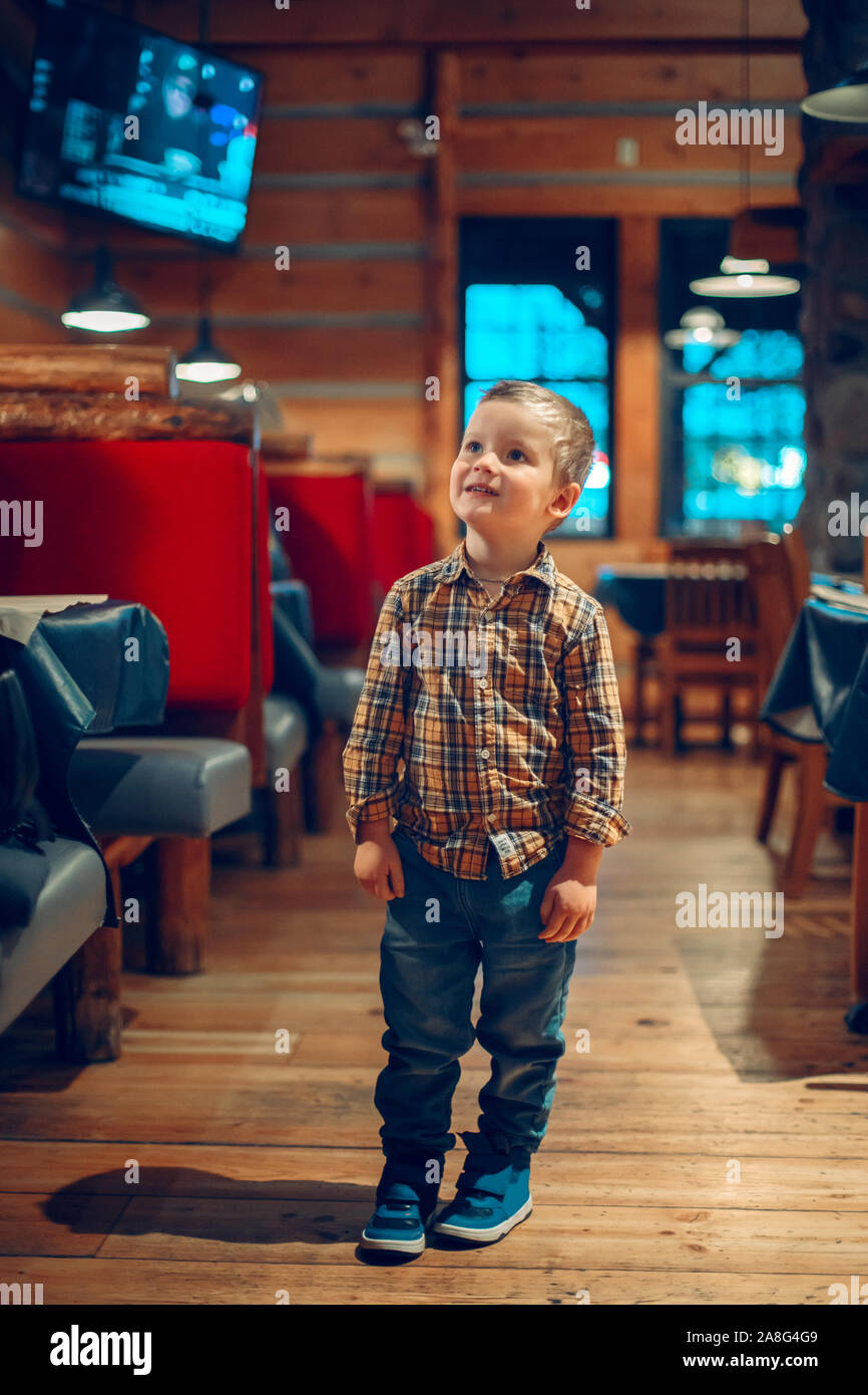 Cute adorable Portrait bébé garçon debout dans un café restaurant à la  chaîne de télévision au programme. Kid trois ans intéressés en version  électronique digita Photo Stock - Alamy