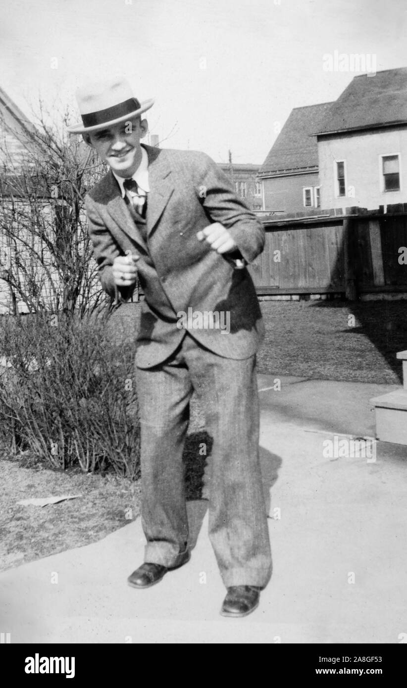 Un jeune homme dapper dans un costume prétendre être la perforation pour un portrait dans l'arrière-cour, ca. L'année 1930. Banque D'Images