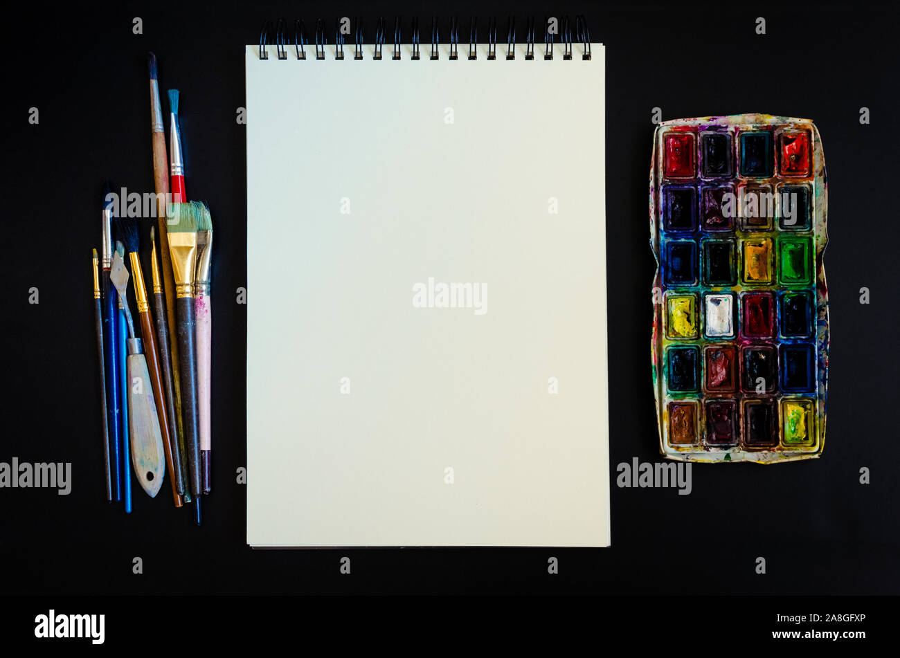 Artiste Créateur de travail télévision lay, immersive. Vue de dessus sur table avec carnet vierge, pinceaux et palettes de colorant. L'Art, atelier, peinture, dessin, Banque D'Images
