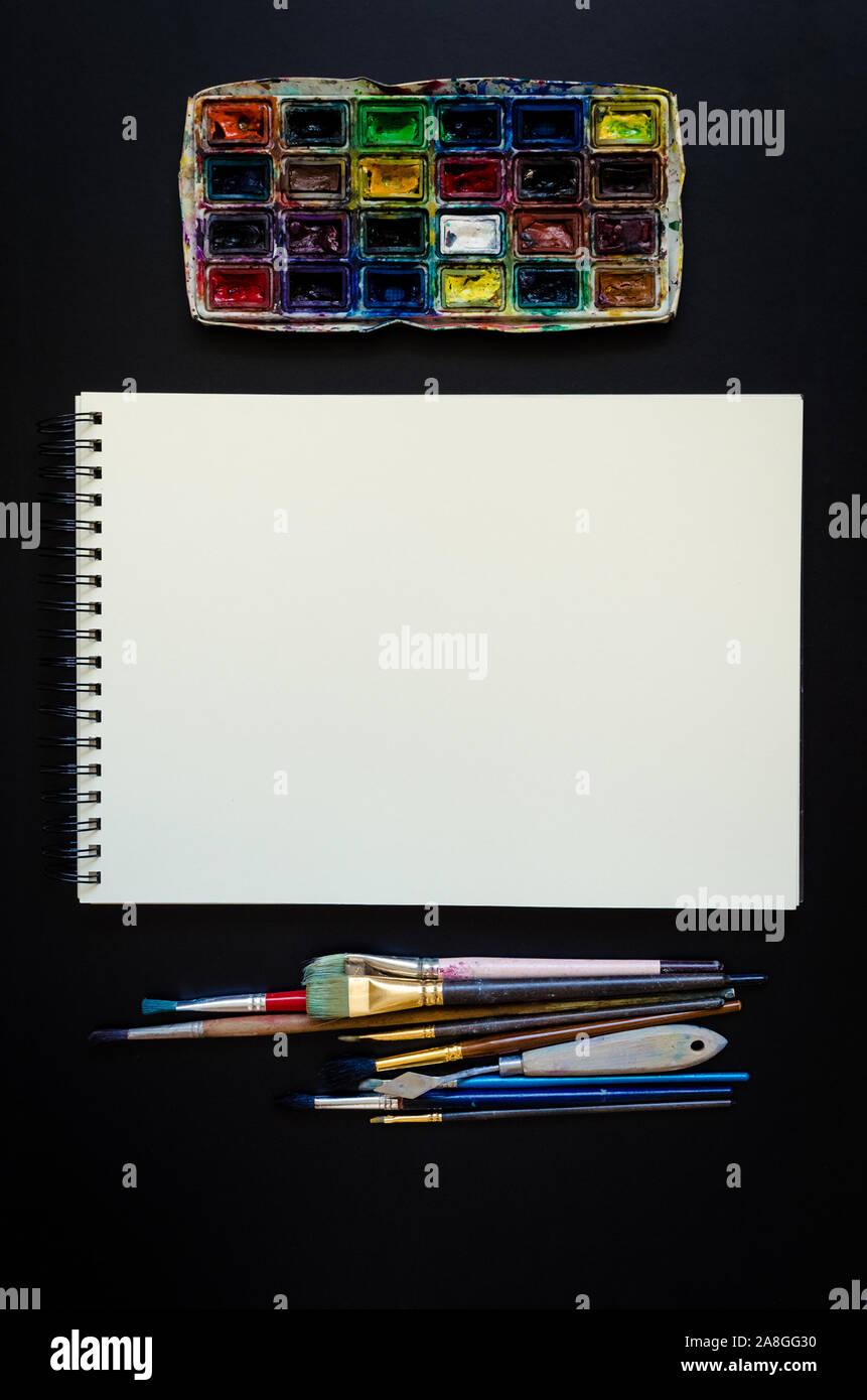 Artiste Créateur de travail télévision lay, immersive. Vue de dessus sur table avec carnet vierge, pinceaux et palettes de colorant. L'Art, atelier, peinture, dessin, Banque D'Images