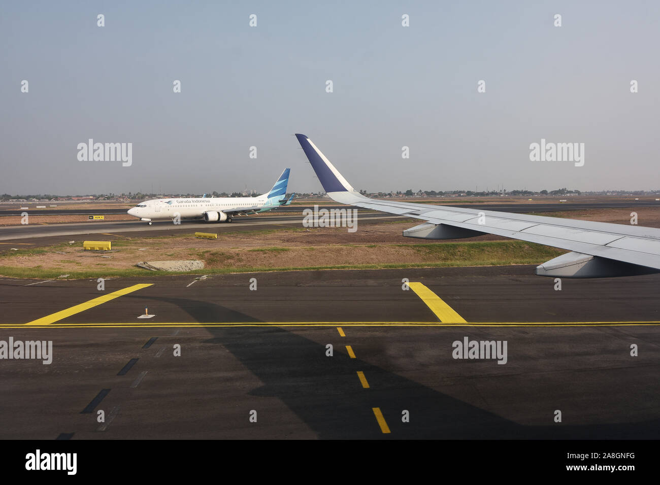 Vue paysage, photo de l'angle,avion Fenêtre Airbus A320, l'aile gauche, Garuda Indonesia Boeing 737 série, dans la voie de circulation pour le décollage Banque D'Images