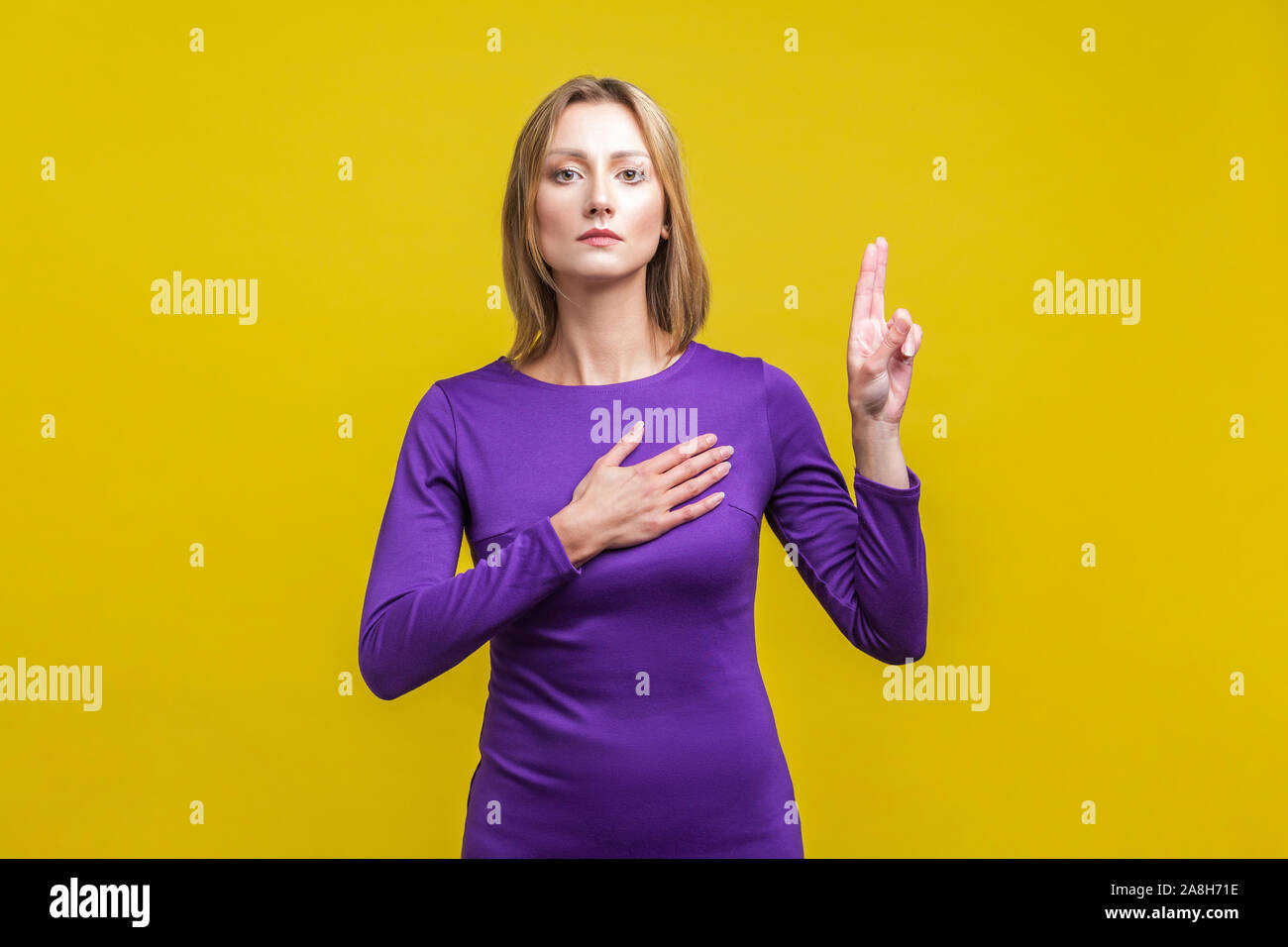 Je le jure ! Portrait de l'honnête citoyen, jeune femme élégante en robe mauve serré debout avec la main sur la poitrine et les doigts vers le haut, en faisant la promesse de fidélité. Banque D'Images