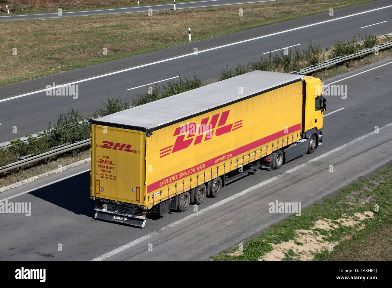 Camion avec remorque DHL curtainside sur autoroute. Banque D'Images