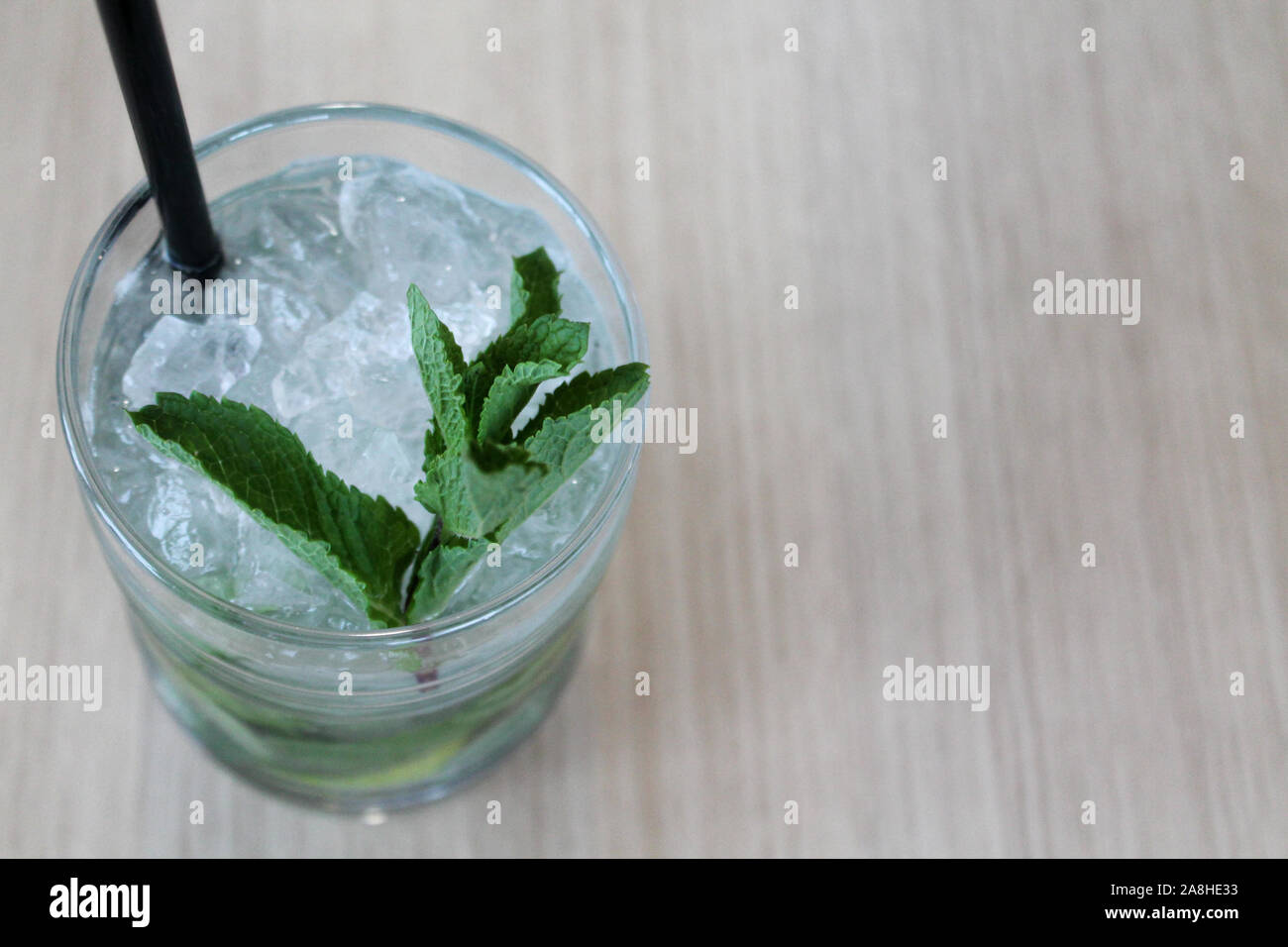 Verre de cocktail mochito sur table en bois avec de la paille noire, de la glace et de feuille de menthe. L'espace de copie pour le texte. Boissons non alcooliques ou et la boisson dans le ba Banque D'Images