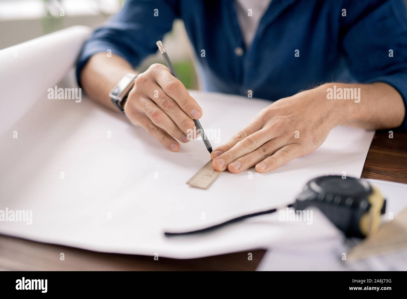 Mains de l'ingénieur mature holding crayon et règle tout en tirant sur le papier en ligne Banque D'Images