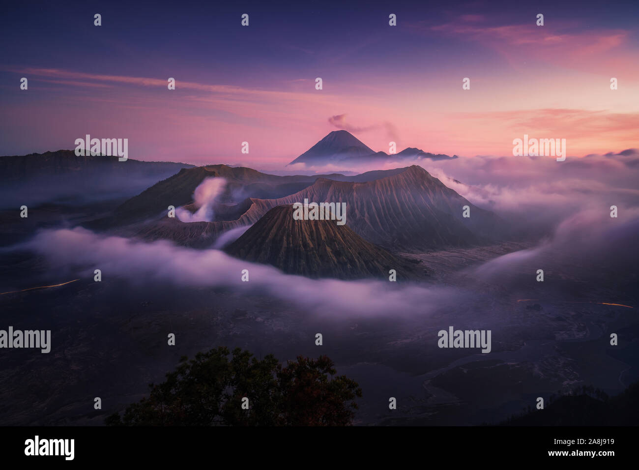 Le Mont Bromo au coucher du soleil. Brouillard dans la caldeira, Semeru, et les nuages de cendre. L'île de Java. L'Indonésie voyage aventure. Banque D'Images