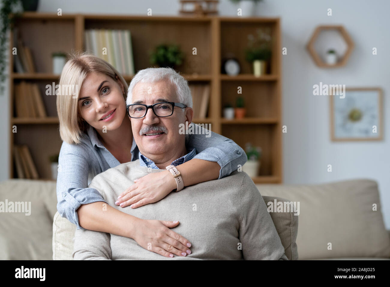 Pretty young woman embracing senior père assis sur la table en face de l'appareil photo Banque D'Images