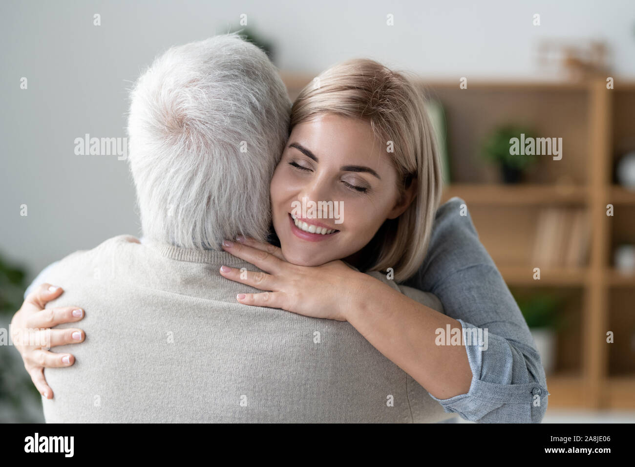 Jeune femme affectueuse avec dents sourire donnant à son père des hug Banque D'Images