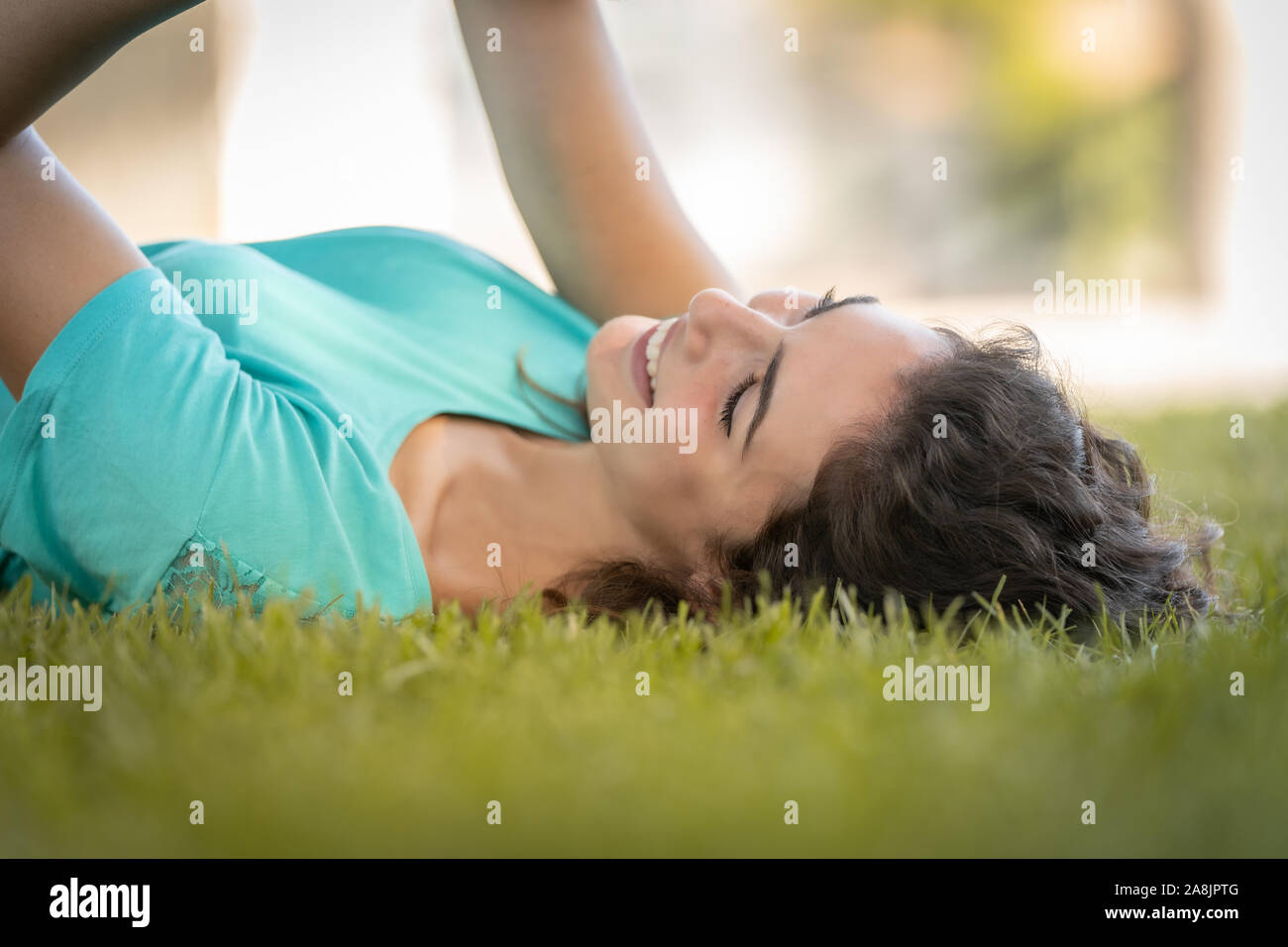 Photographe girl lying on the grass heureux et souriant, relaxant Banque D'Images