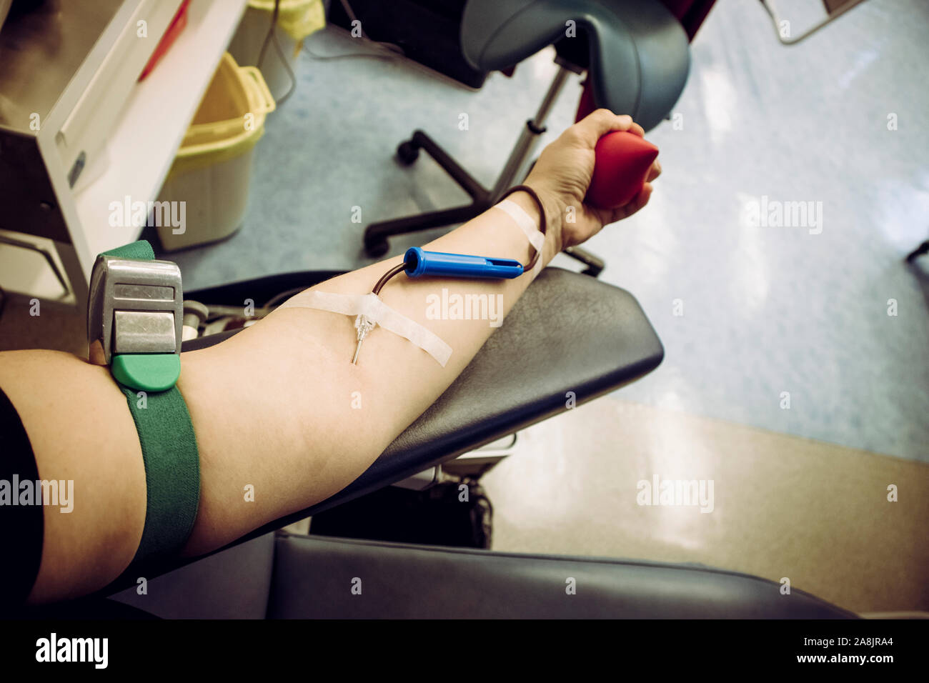 Selective focus sur la main du bras de femme avec aiguille à l'intérieur de la peau, le sang qui coule à travers le don d'équipement. Une femme heureuse le don de sang des donneurs c Banque D'Images