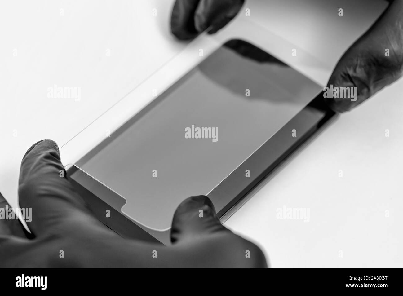 Un homme est l'installation d'une vitre de protection sur l'écran d'un smartphone. Banque D'Images