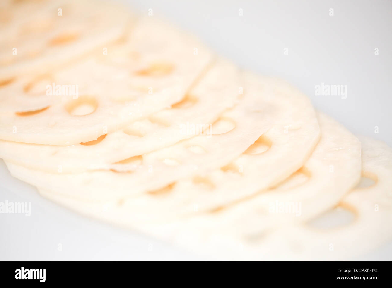 Tranches de racines de lotus fraîches sur fond blanc - ingrédients asiatiques (isolé) - Image Banque D'Images