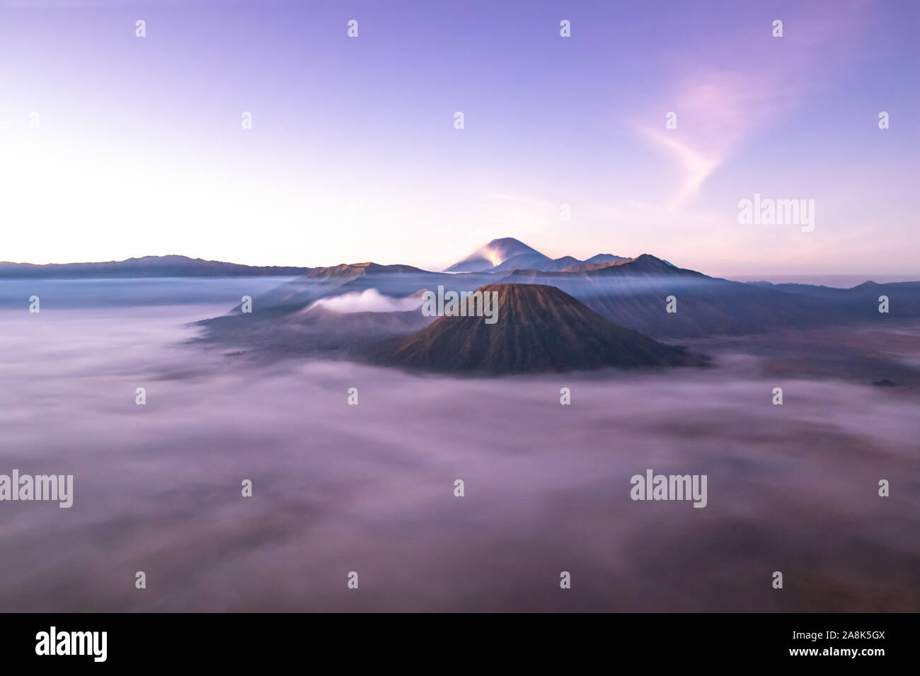 Le Mont Bromo au lever du soleil ; île de l'Est de Java, Indonésie. La couverture de nuages de gaz s'échappant de la vallée ; le cratère. Banque D'Images