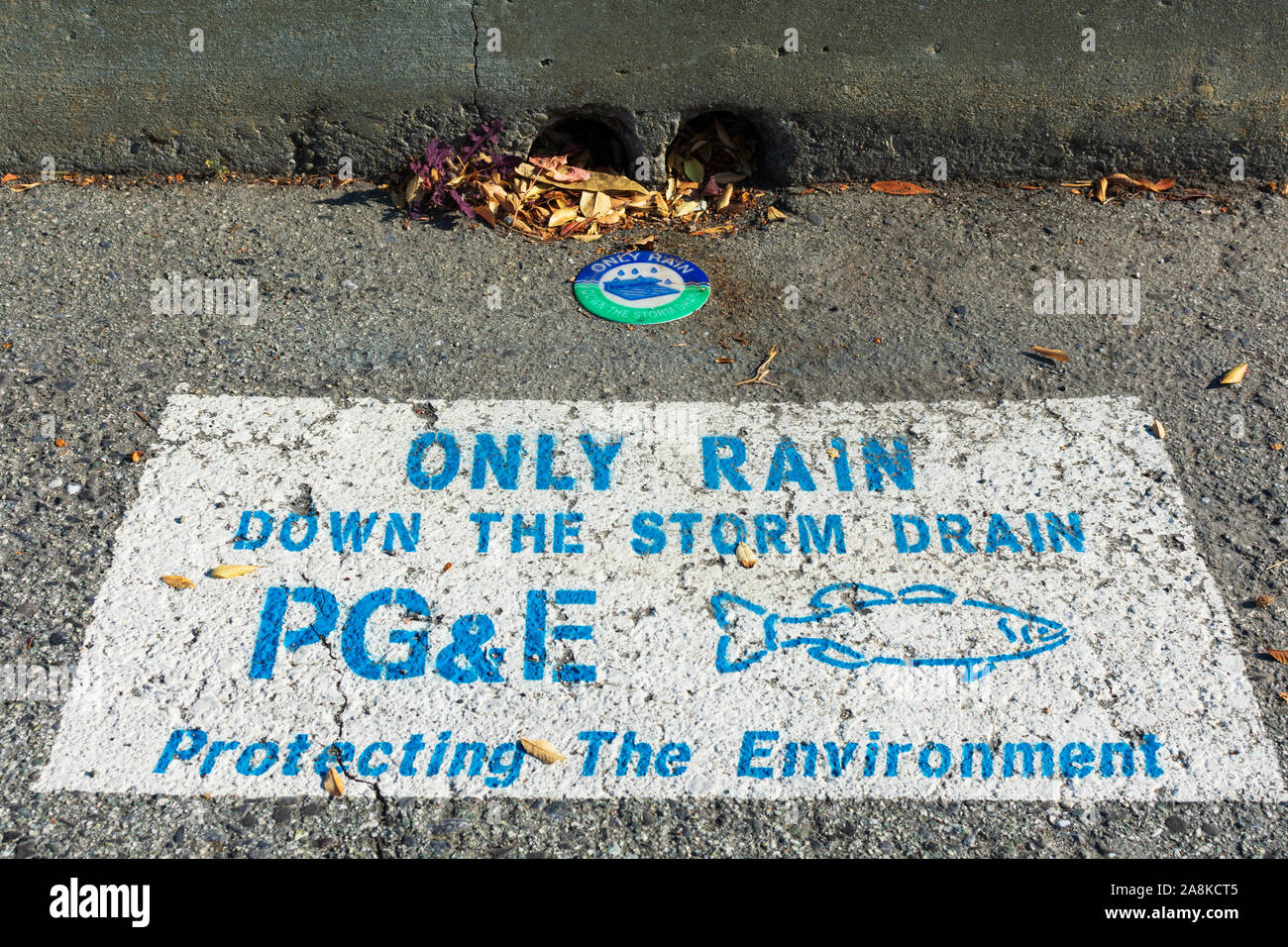 Pluie, jusqu'à seulement d'eaux pluviales avertissement PG&E,Pacific Gas and Electric Company, près de l'entrée d'évacuation de la rue. La silhouette du poisson. La protection de l'environnement Banque D'Images