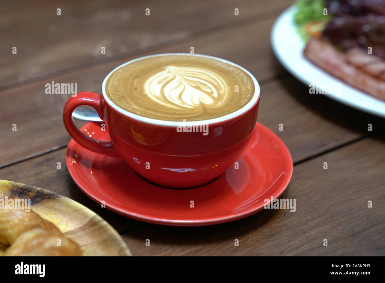 Télévision avec café blanc motif coeur dans une tasse rouge et par t de croissant et bacon salade par le côté. Breakfast set concept. Banque D'Images