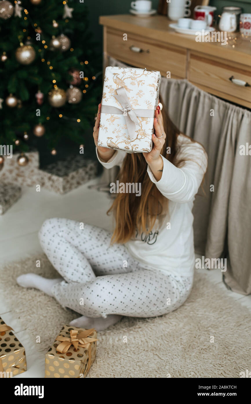 Jeune femme présente de décoration avec du papier d'emballage avant Noël à la maison Banque D'Images