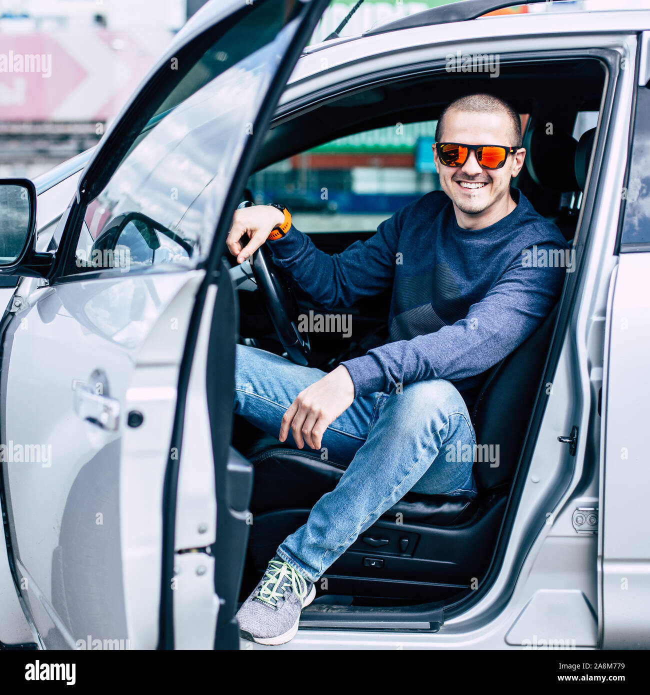 L'Homme à lunettes dans la voiture et souriant Banque D'Images
