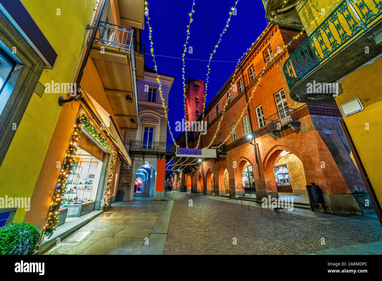 Rue piétonne pavée avec illumination de Noël dans la vieille ville d'Alba dans le Piémont, Italie du Nord. Banque D'Images