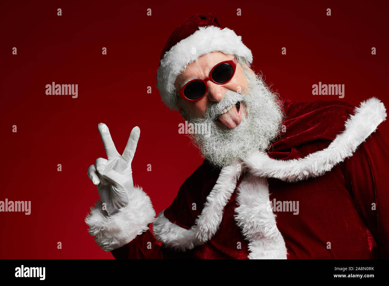 Taille portrait de funky Santa portant des lunettes de soleil et smiling at camera prêt à profiter d'une fête de Noël, copy space Banque D'Images