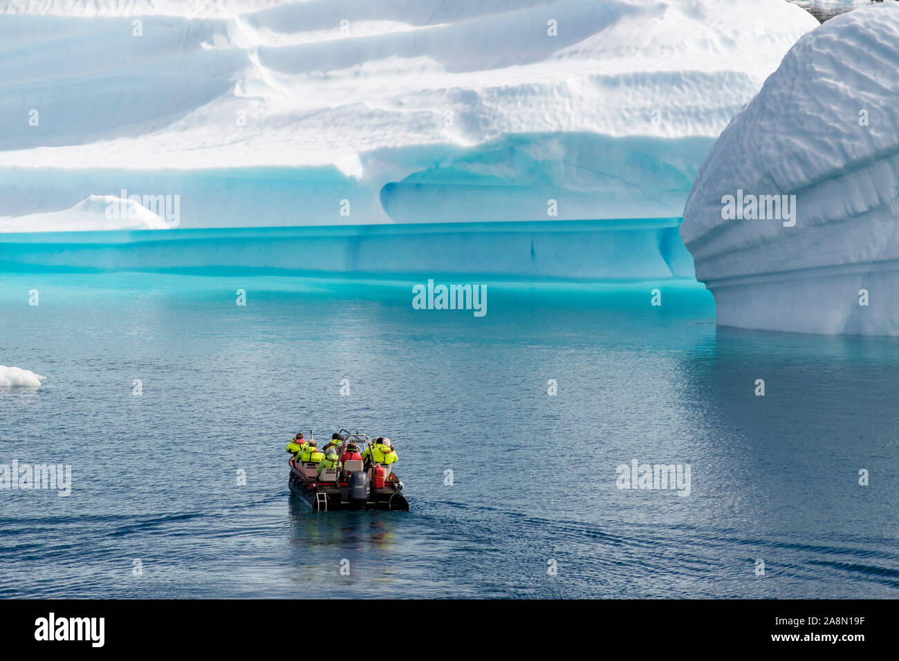 Les touristes dans un petit bateau à voile à proximité de grands Icebergs de fjord Tunulliarfik en été. Narsaq Kujalleq, le sud du Groenland, Banque D'Images