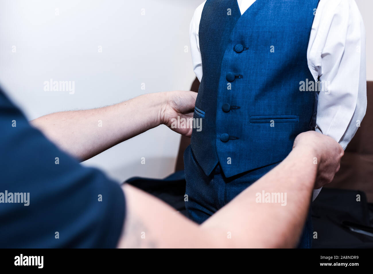 Un père aide à habiller son fils dans son manteau à la taille et à l'uniforme sur son mariage, congé parental, un joli moment de la paternité Banque D'Images