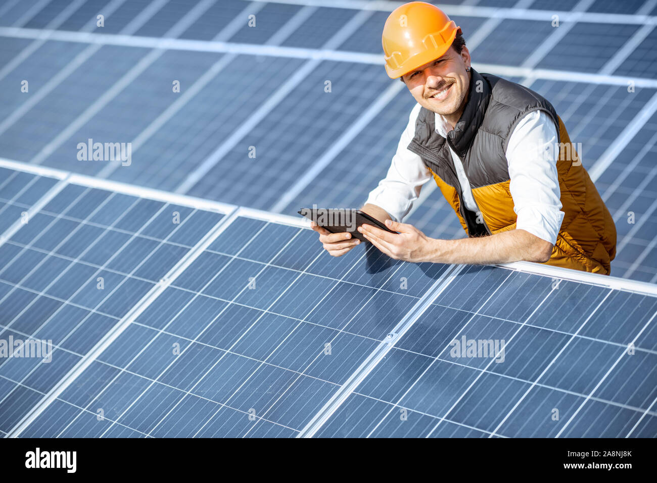 Portrait of a happy ingénieur au casque de protection article with digital tablet sur une centrale solaire. Station solaire concept développement Banque D'Images