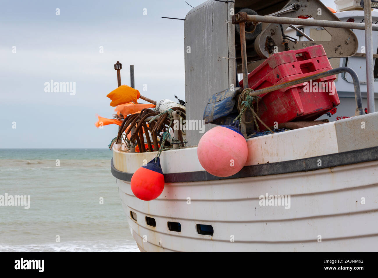 Bateau de pêche en bois blanc avec des ailes colorées sur la plage de Hastings pris en mars. Banque D'Images