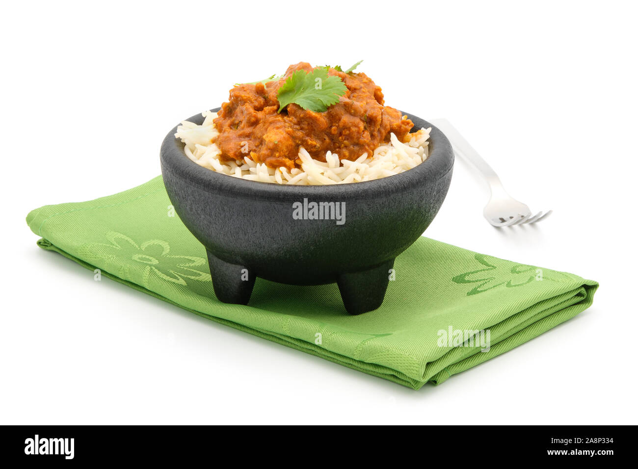 Portion de poulet au beurre indien garni de coriandre fraîche sur un lit de riz basmati sur un fond blanc. Banque D'Images