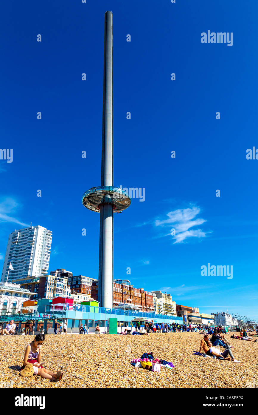 Des gens assis sur la plage avec le 162m de haut de la tour d'observation i360 de British Airways sur le front de mer, Brighton, UK Banque D'Images