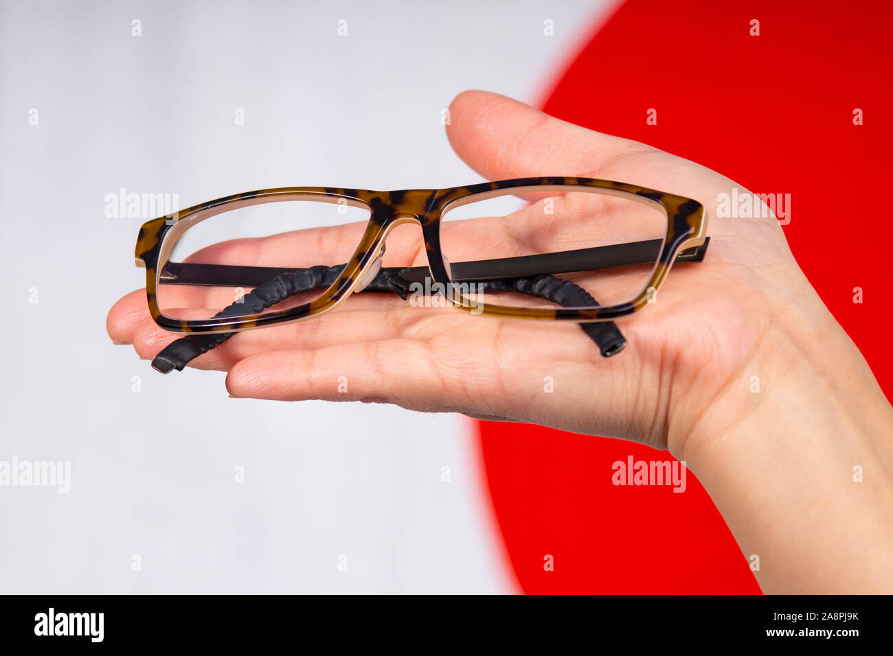 Close up of hand holding une paire de lunettes avec un drapeau du Japon Banque D'Images