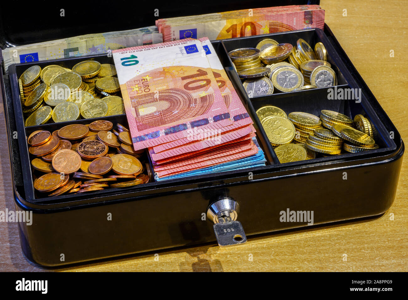 Une petite caisse remplie de pièces de monnaie et de billets Photo ...