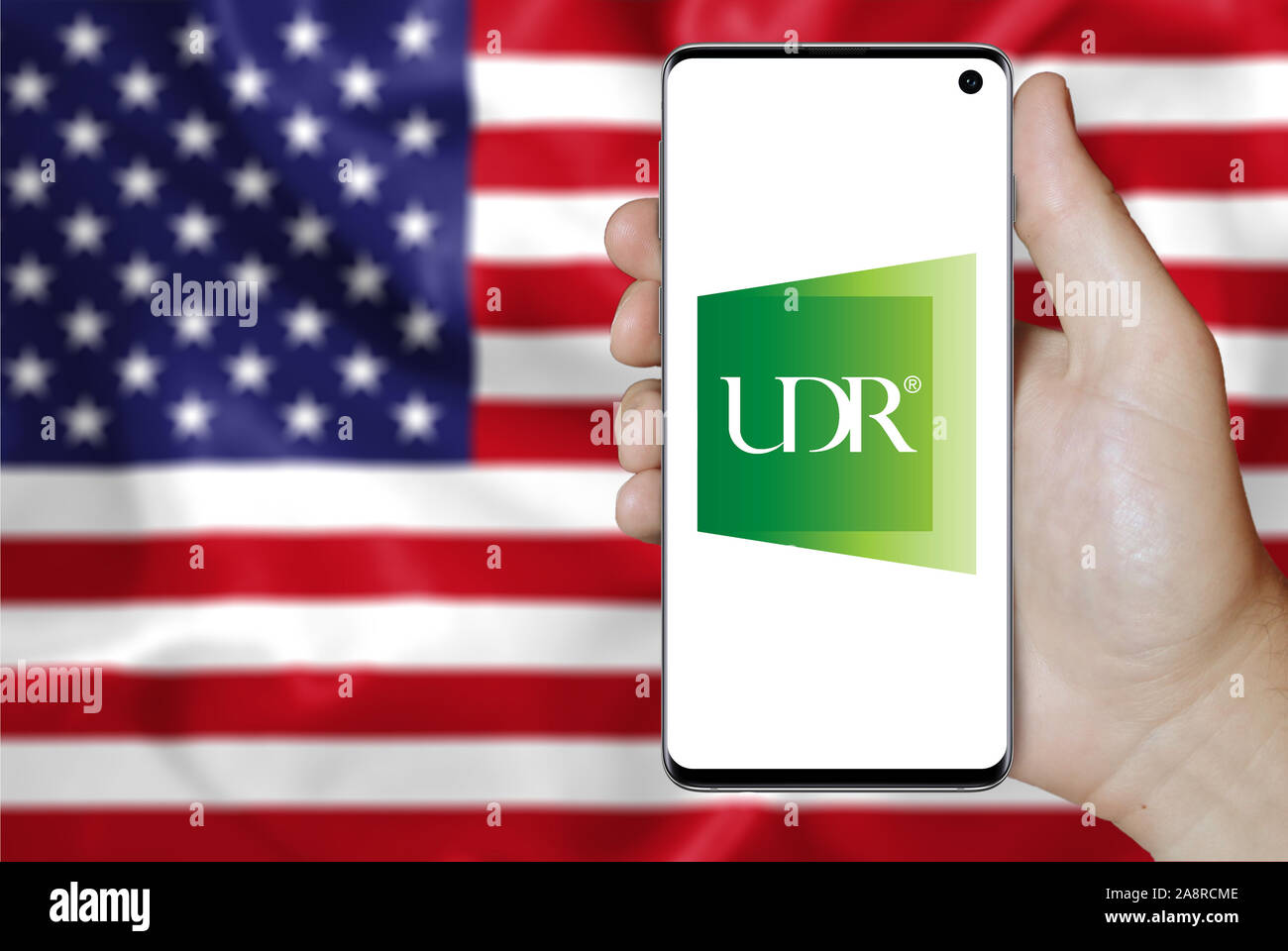 Logo de compagnie publique UDR, Inc. affiché sur un smartphone. Pavillon de l'USA historique. Credit : PIXDUCE Banque D'Images