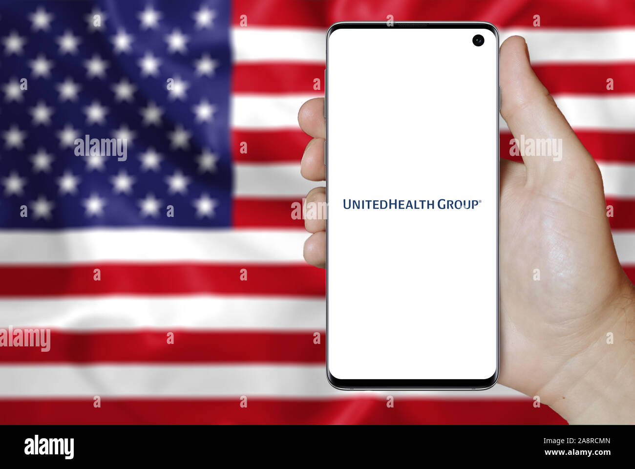 Logo de compagnie publique United Health Group Inc. affiché sur un smartphone. Pavillon de l'USA historique. Credit : PIXDUCE Banque D'Images
