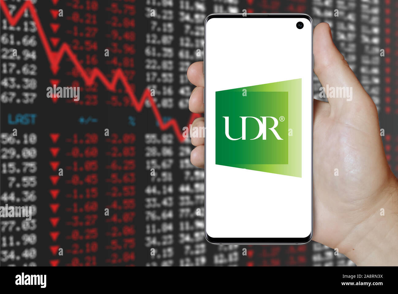 Logo de compagnie publique UDR, Inc. affiché sur un smartphone. Contexte du marché boursier négatif. Credit : PIXDUCE Banque D'Images