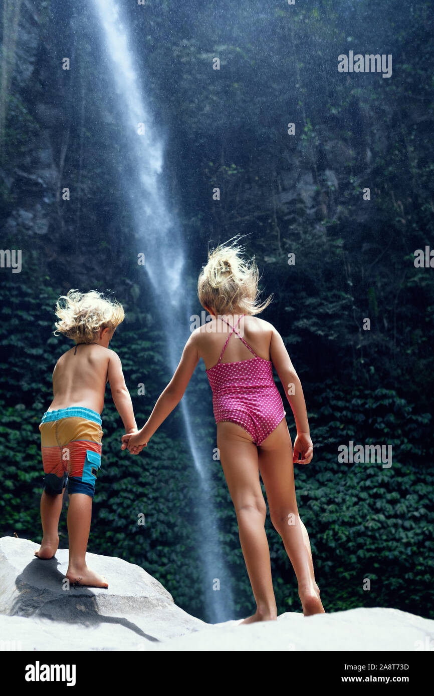 Dans la jungle tropicale ou une sœur se tenir sous une cascade, explorer la nature de la forêt tropicale. Voyage d'aventure pour les enfants, randonnée activité. Le style de vacances en famille. Banque D'Images
