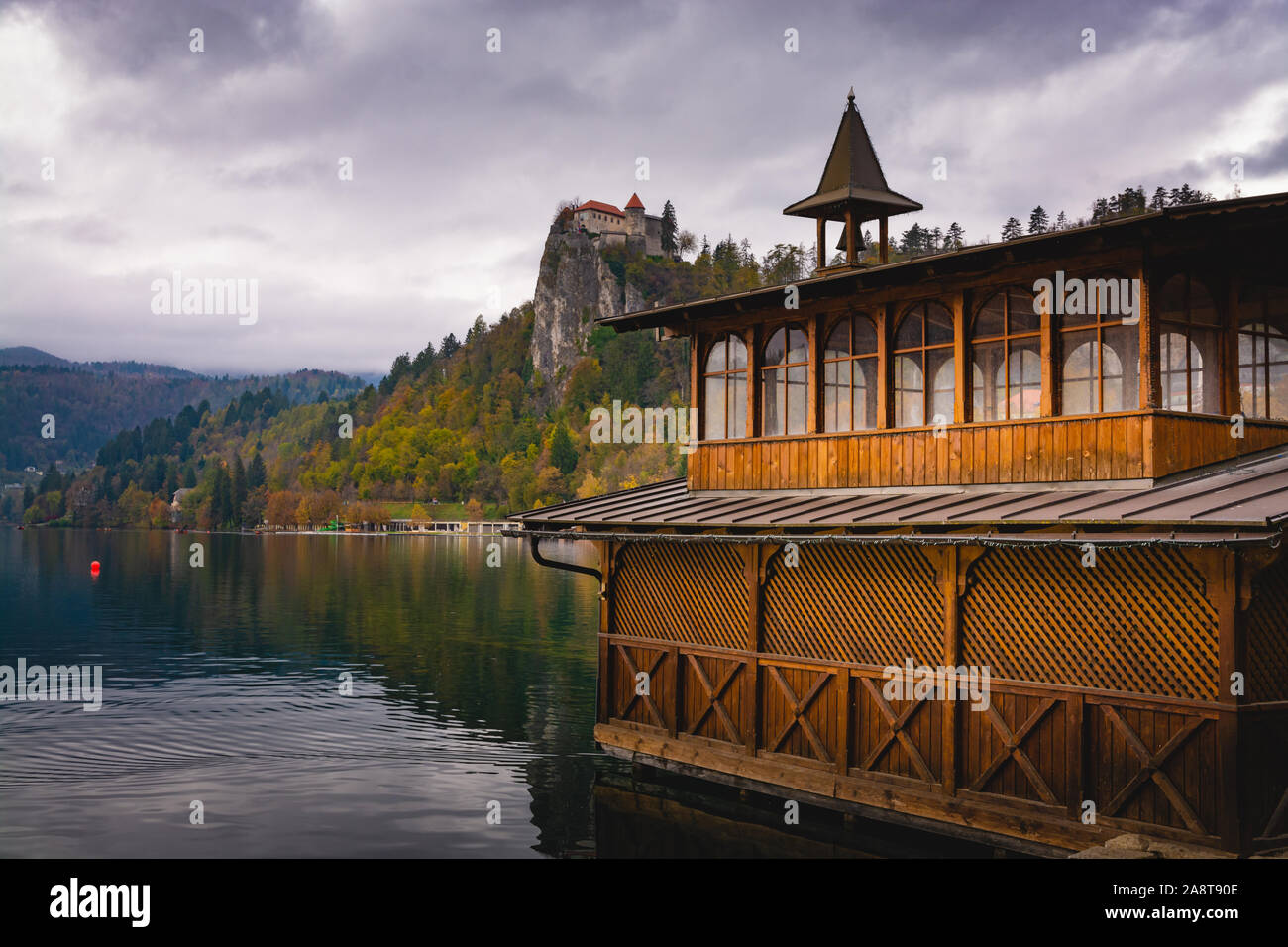 Un hangar à bateaux au lac de Bled (Slovénie) dans un jour nuageux en automne. Le Château de Bled sur une falaise à l'arrière-plan Banque D'Images