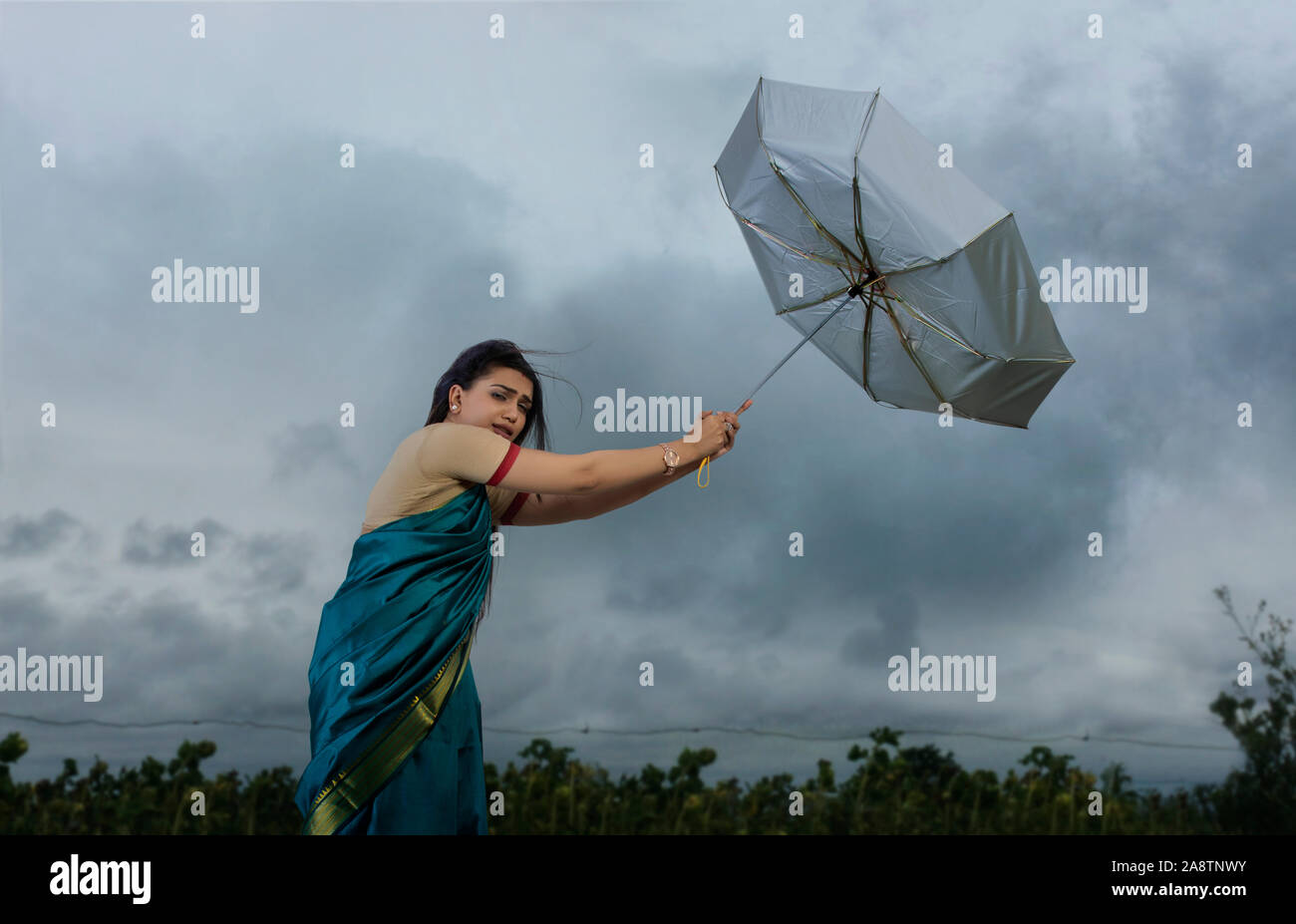 Femme essayant de tenir sur le parapluie en cas de mauvais temps Banque D'Images
