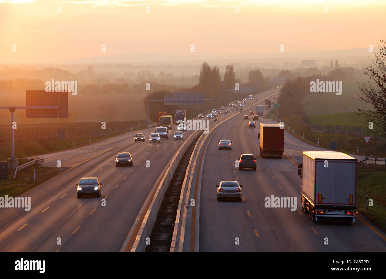 Voitures sur route autoroute au coucher du soleil Banque D'Images