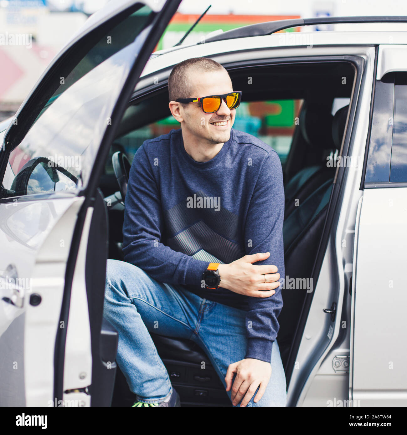 L'Homme à lunettes rouges adultes dans la voiture avec les portes ouvertes Banque D'Images