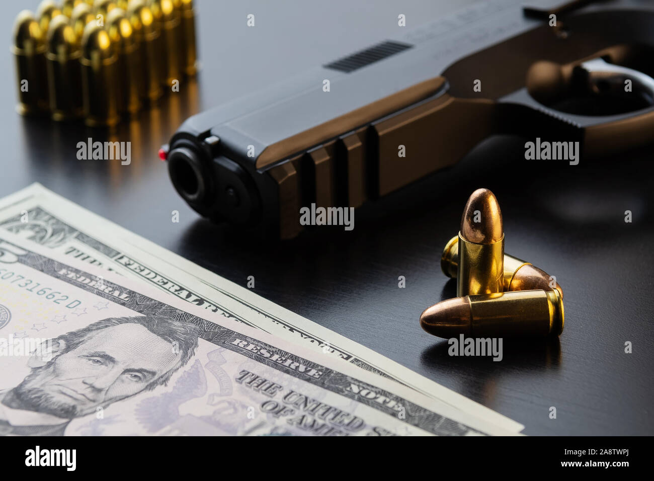 9 mm pistolet semi-automatique, full metal jacket les balles et les billets de dollar sur fond noir. Maquette conceptuelle du contrôle des armes à feu et le crime. Banque D'Images