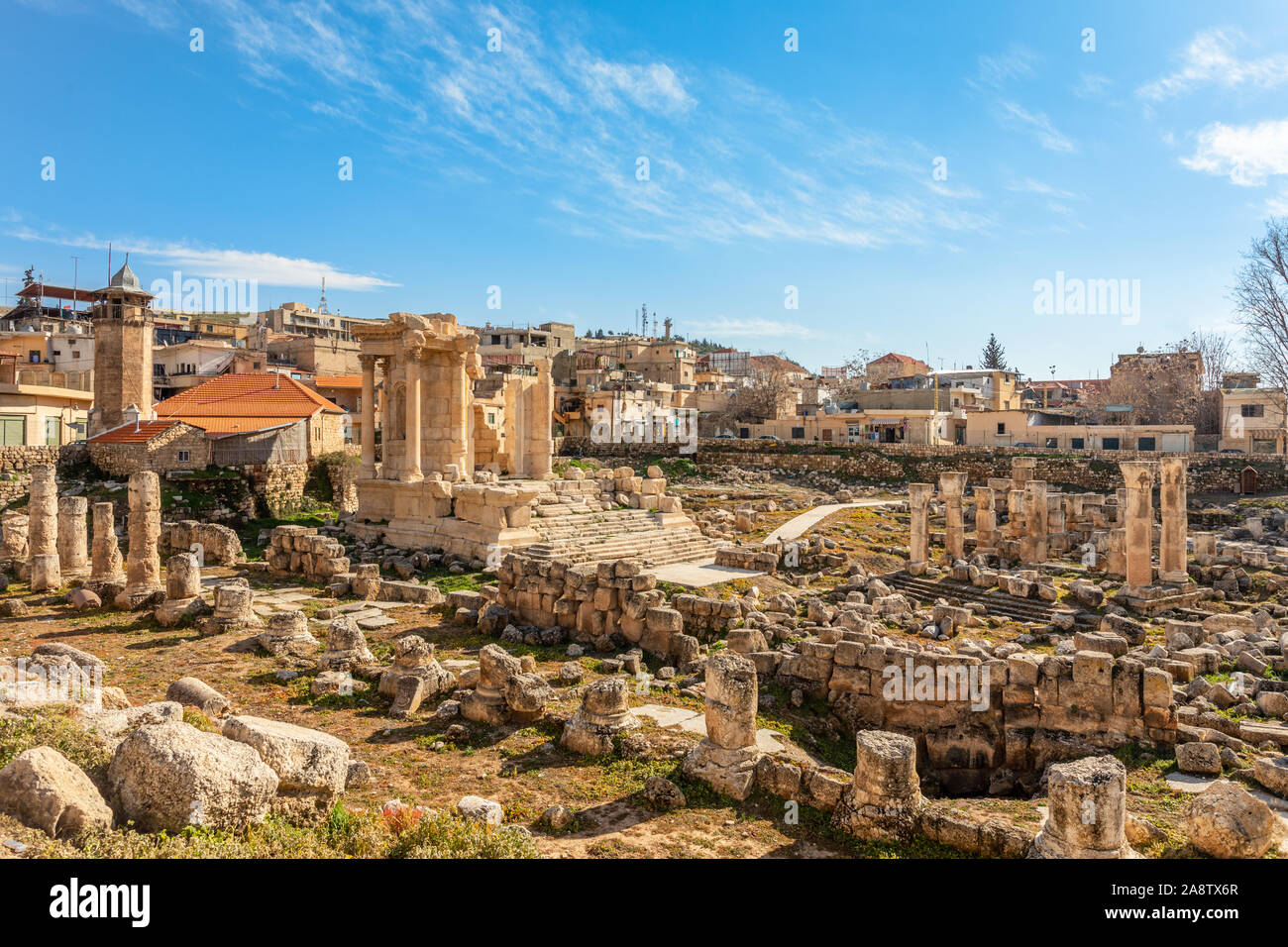 Les ruines et ne font que fragmenter de temple de Vénus à gauche avec des maisons modernes et de ciel bleu en arrière-plan, vallée de la Bekaa, Baalbeck, au Liban Banque D'Images