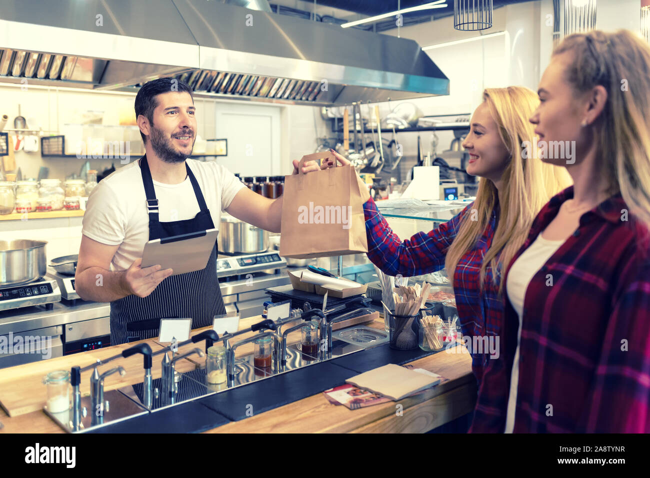 Serveur qui sert de la nourriture à emporter aux clients au comptoir dans petite famille eatery restaurant Banque D'Images