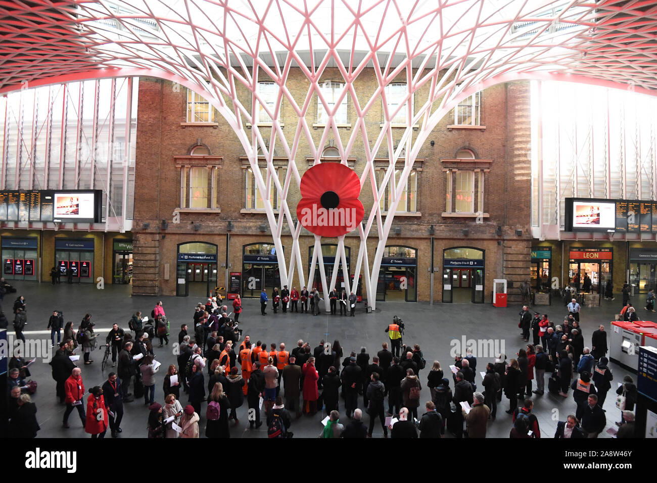 Un grand modèle d'un coquelicot sur l'affichage au King's Cross St Pancras à Londres, comme les gens observent un silence pour marquer le Jour de l'Armistice, l'anniversaire de la fin de la Première Guerre mondiale. Banque D'Images