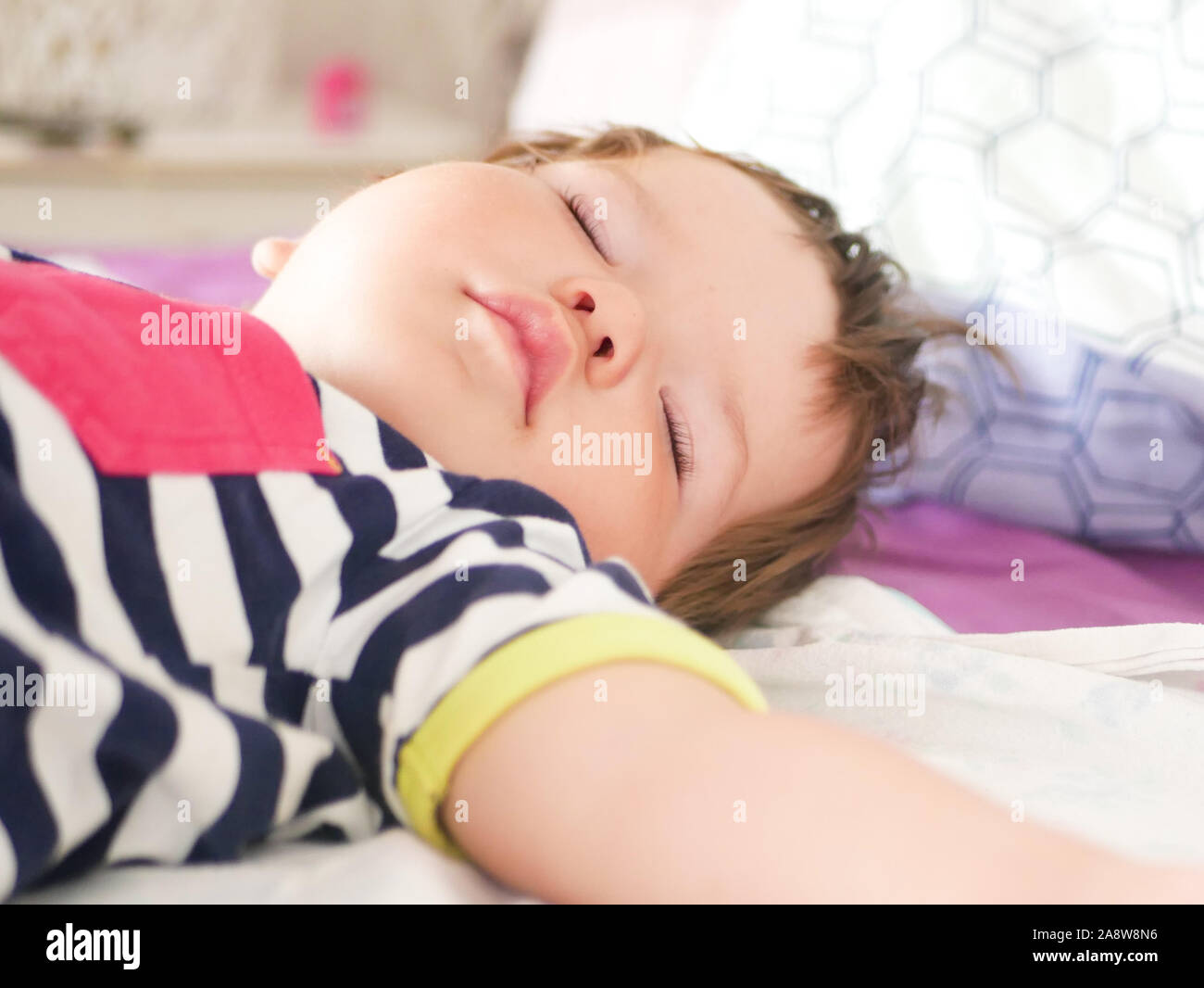 Le sommeil diurne pour les enfants. Funny baby sleeping sur l'arrière du lit à la maison. Position de la journée de l'enfance. Un sommeil sain. Bras tendus pendant le sommeil Banque D'Images